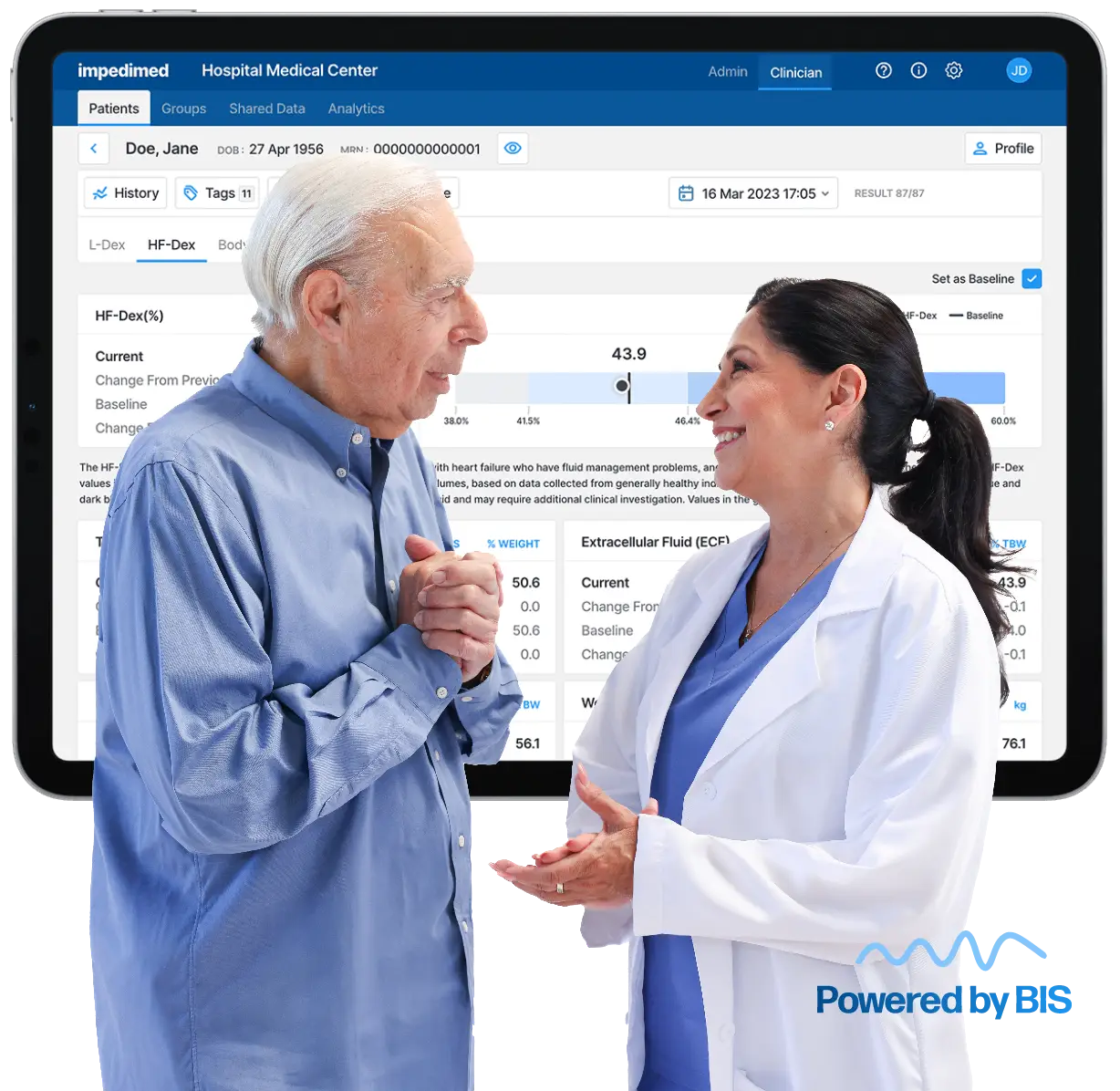 Two healthcare professionals, an elderly man and a clinician, discuss a medical dashboard displayed on a large monitor showing patient data.