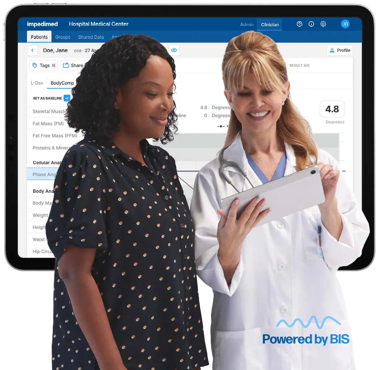 Doctor and patient review a tablet together in front of a medical software dashboard on a screen at a hospital setting